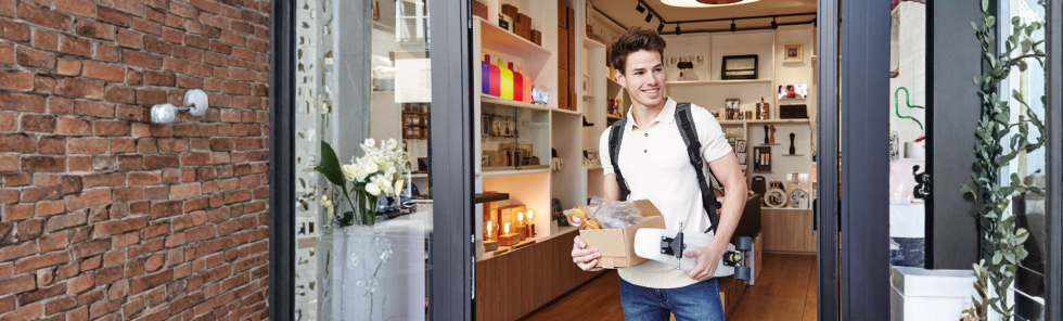Un client sort d'un relais commerçant avec un colis
