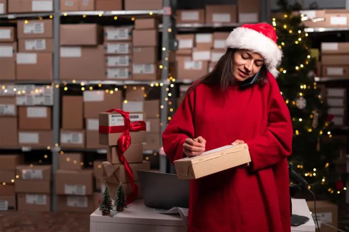 E-commercante en tenue de noël qui se prépare à envoyer les colis